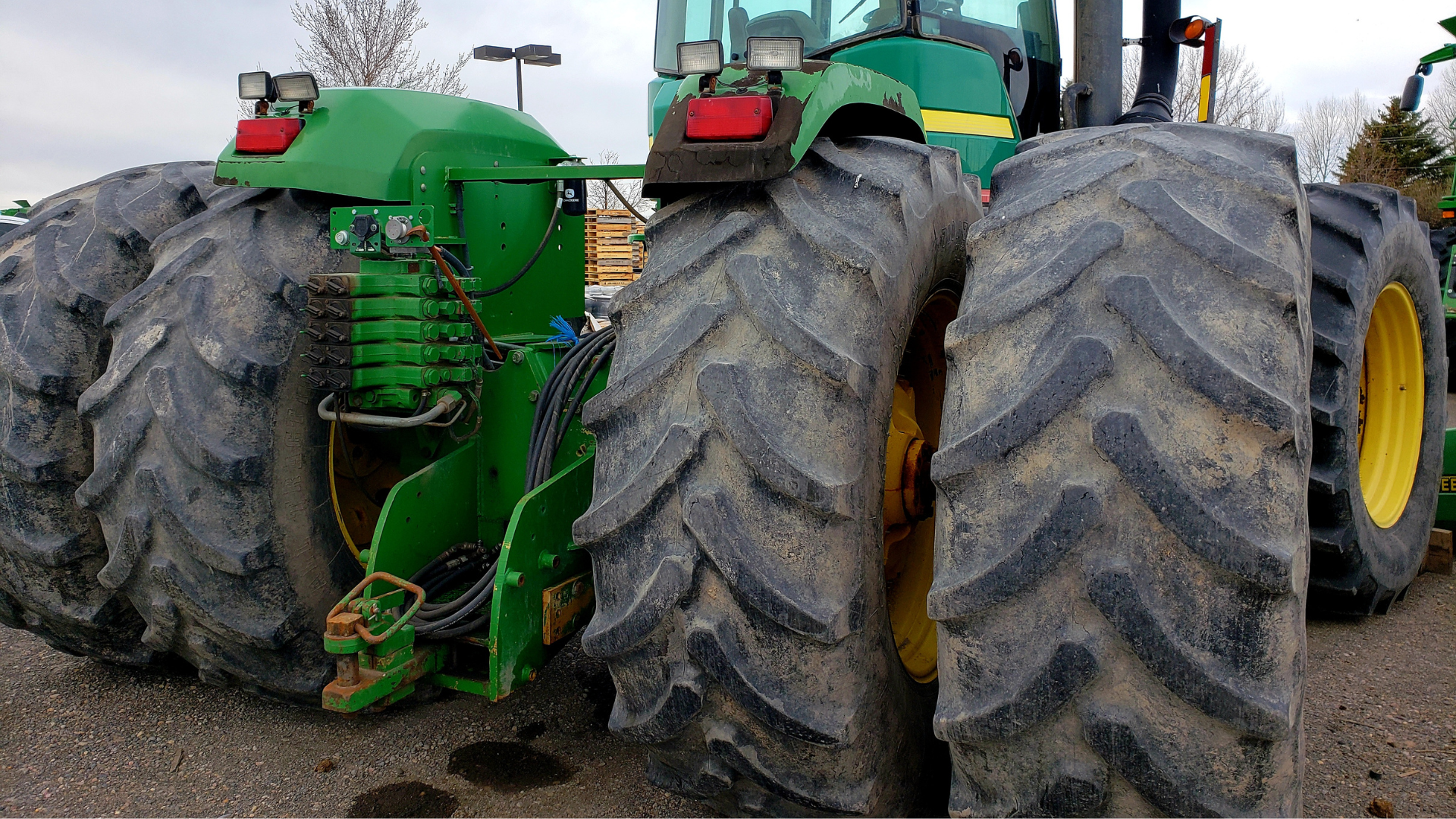 Two tractors are parked next to each other on a dirt road.