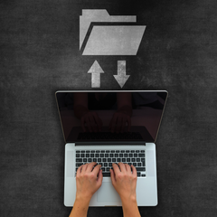 Laptop with hands typing, arrows pointing to/from a folder icon above.