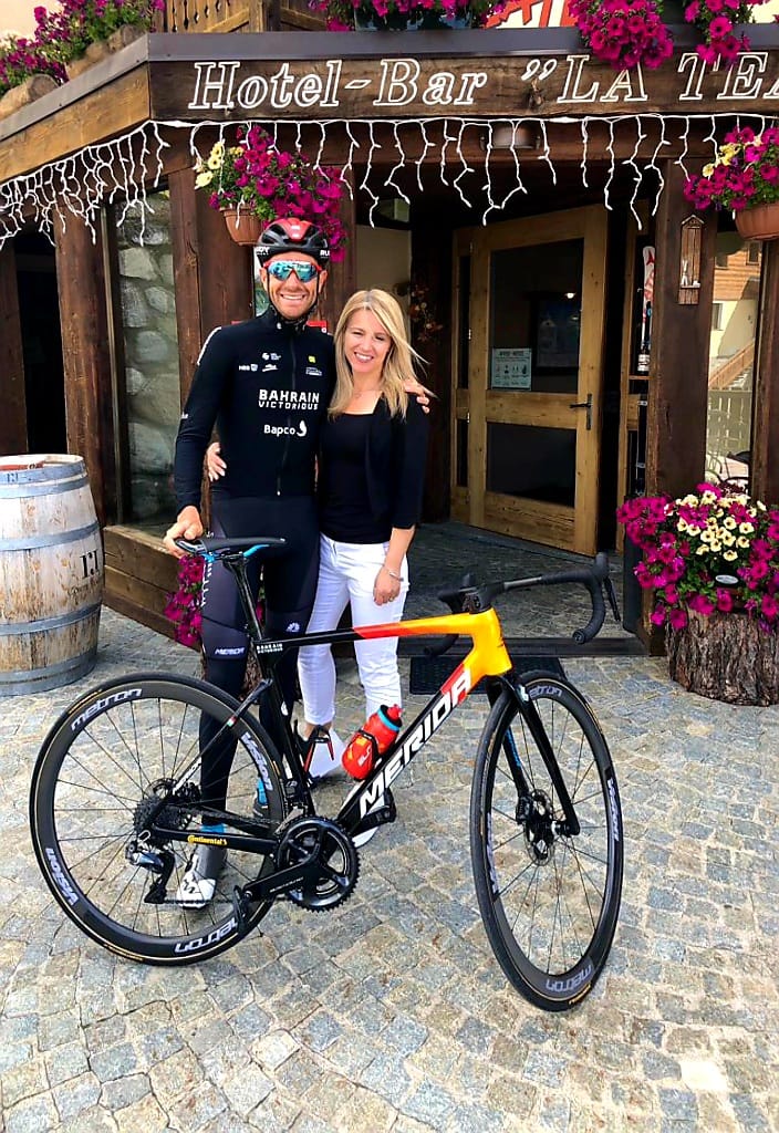 Uomo in tenuta da ciclista e donna in posa con una bicicletta davanti all'