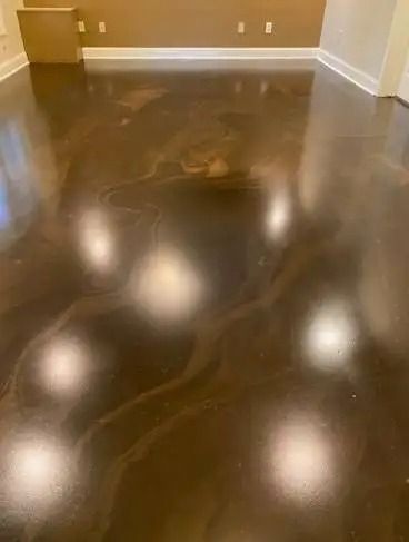Shiny, dark brown metallic epoxy flooring in a room, reflecting light and creating abstract patterns.