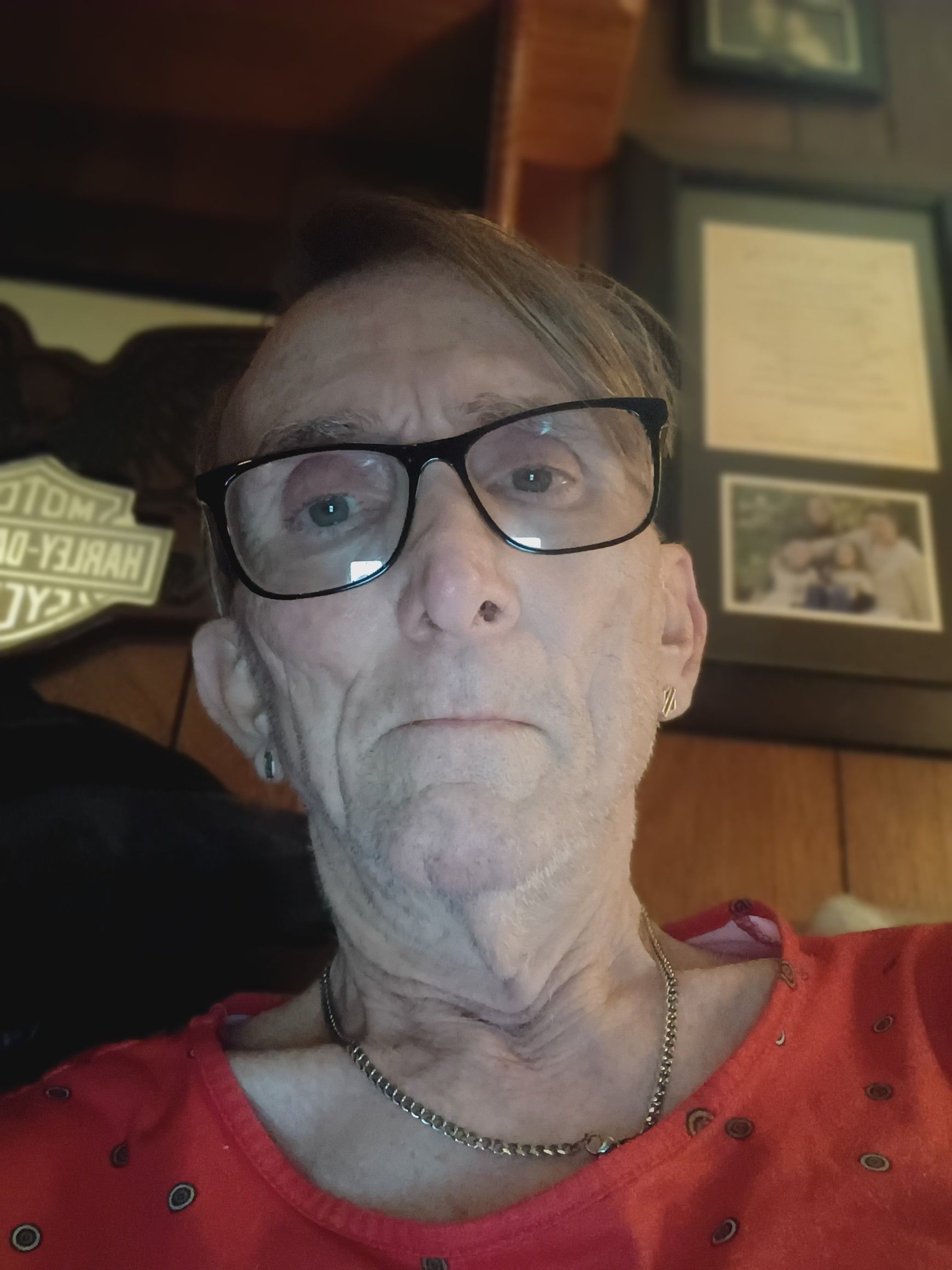 An older white trans women with glasses smiling at the camera