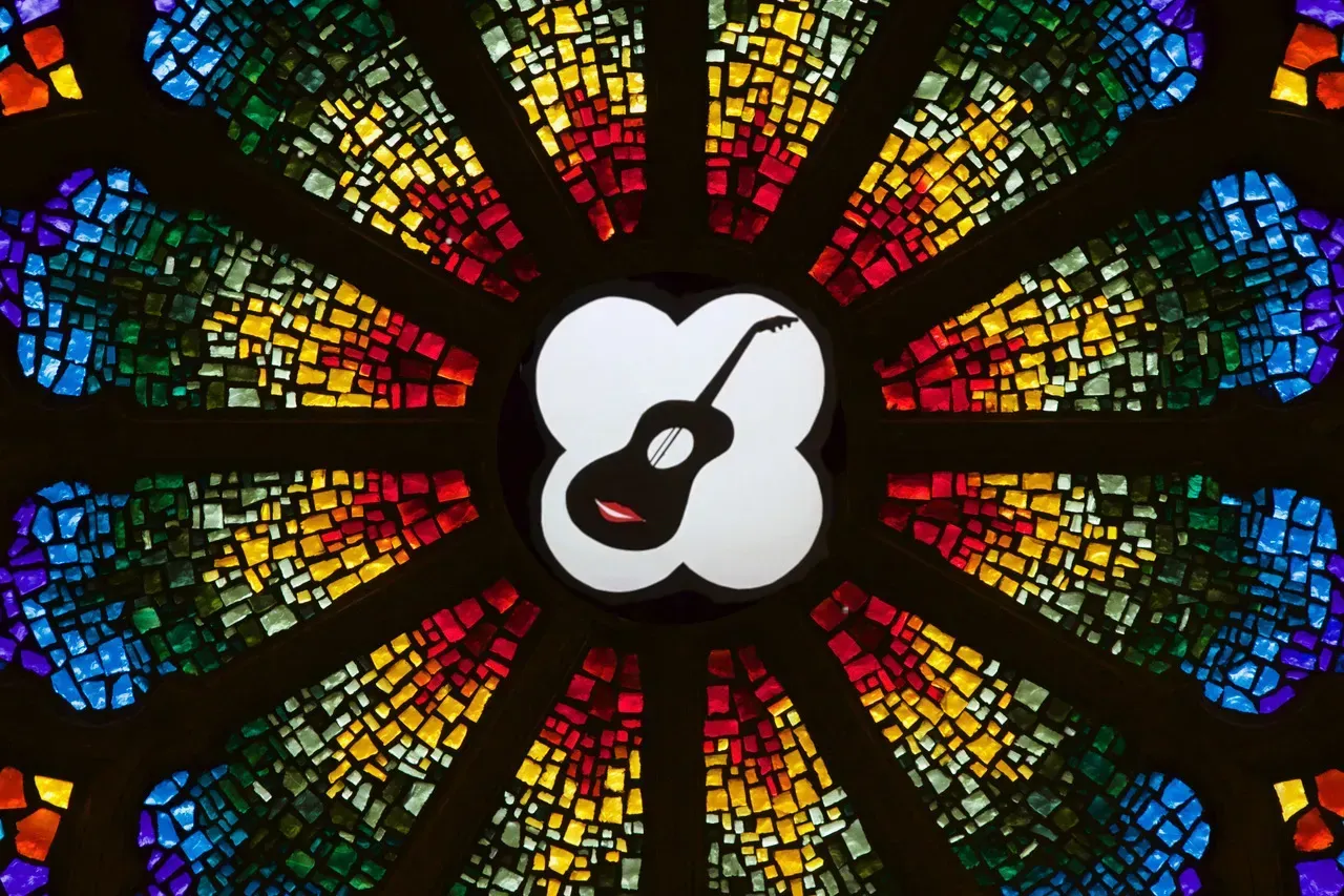 Rose window with a stylized chalice in the center that is a symbol for folk music.