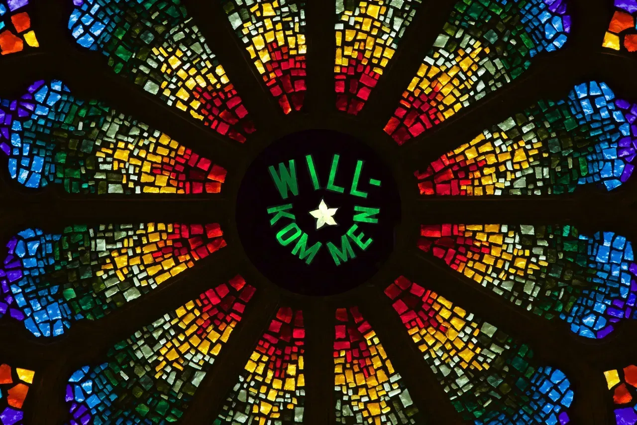 Rose window with text in Green that says Will-Kom Men and a white star in the center.