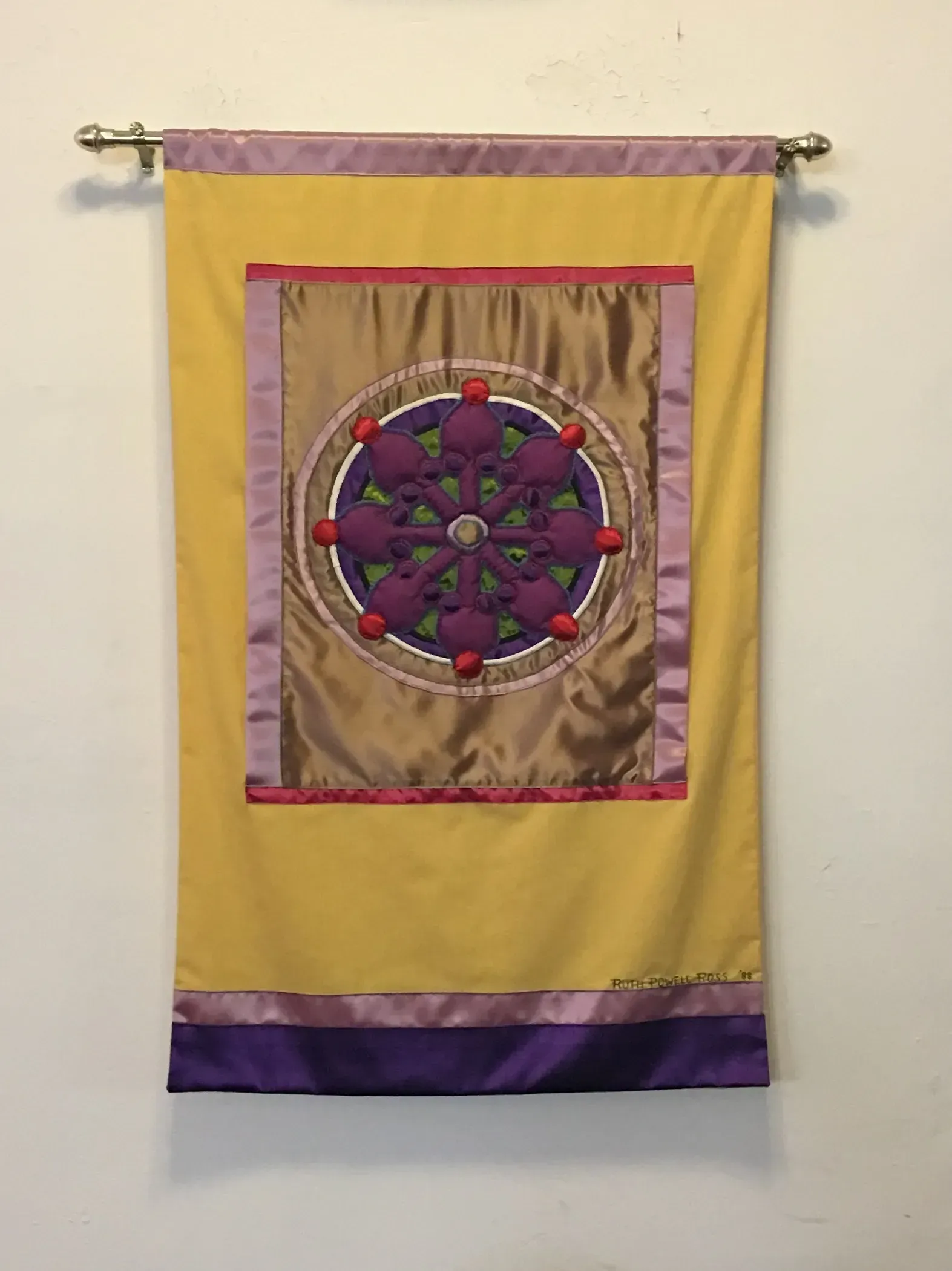 Yellow banner with a purple and gold inner banner with a purple wheel to represent Buddhism