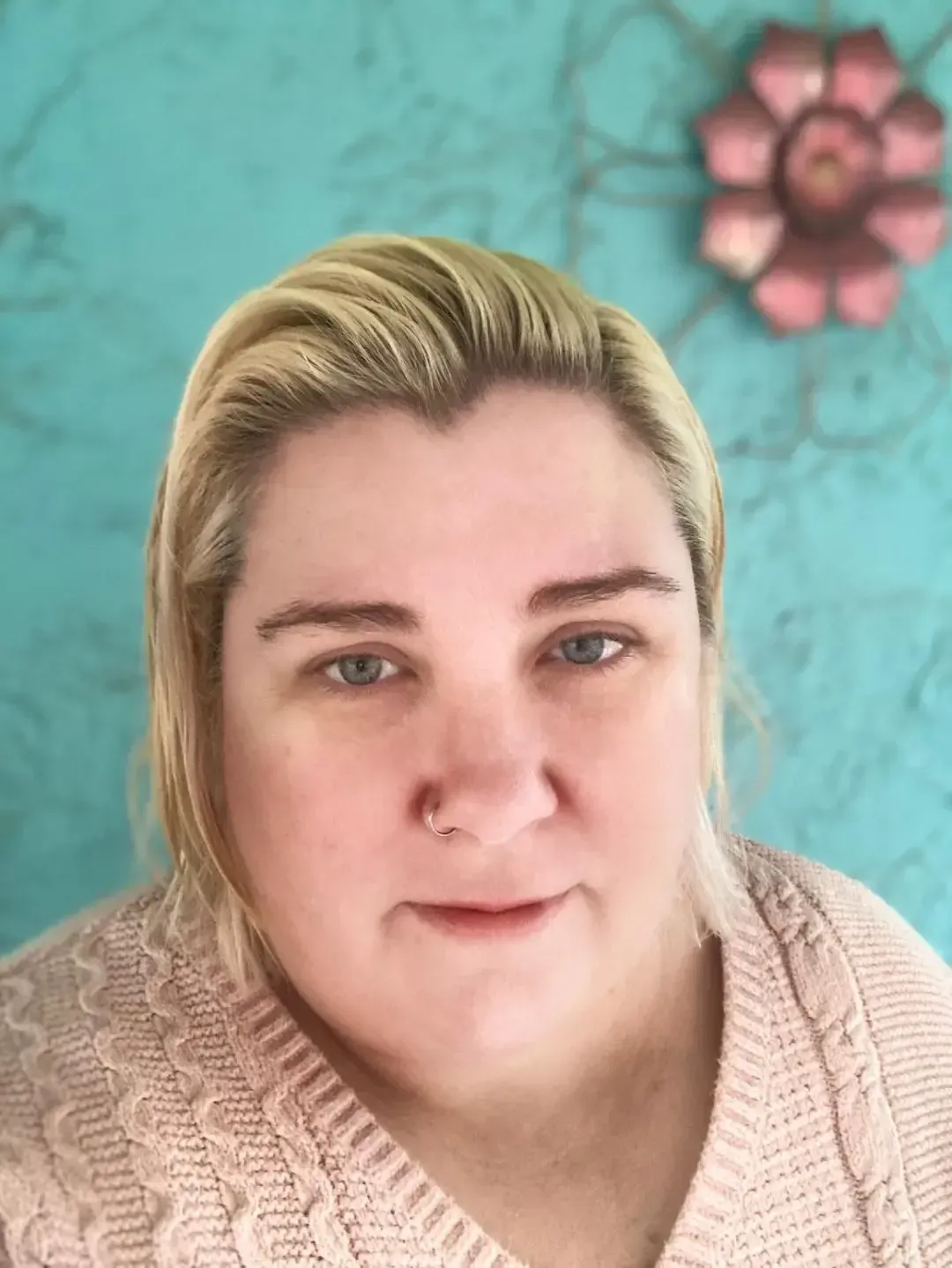 Middle aged white woman with bleach blonde hair in front of a blue background