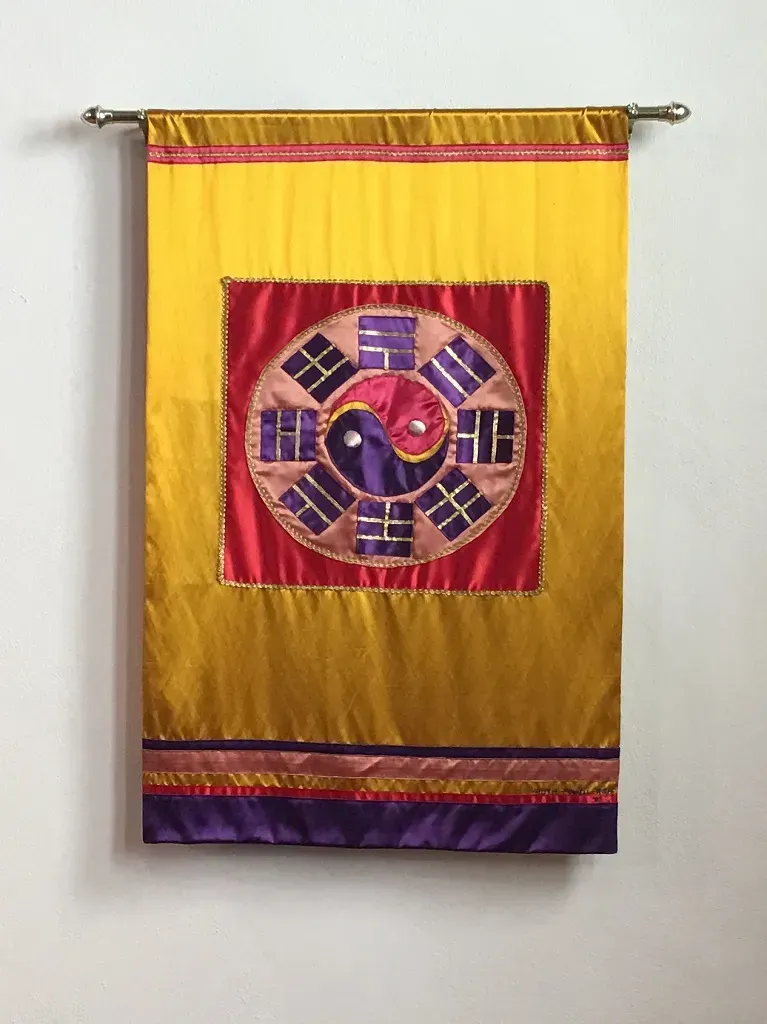 Yellow banner with red inner banner with a ying yang of purple and pink in the center