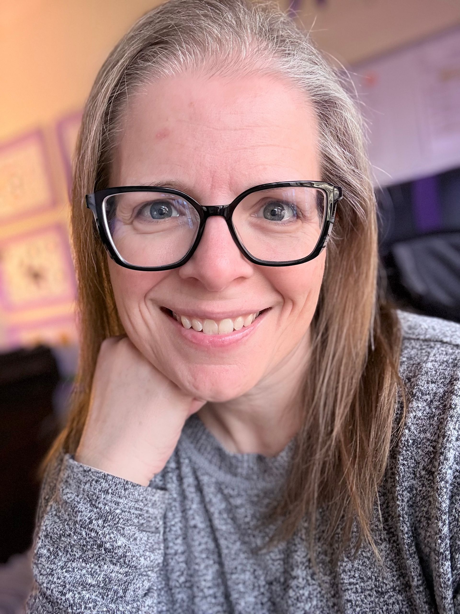 White middle aged woman with gray blonde hair with dark framed glasses