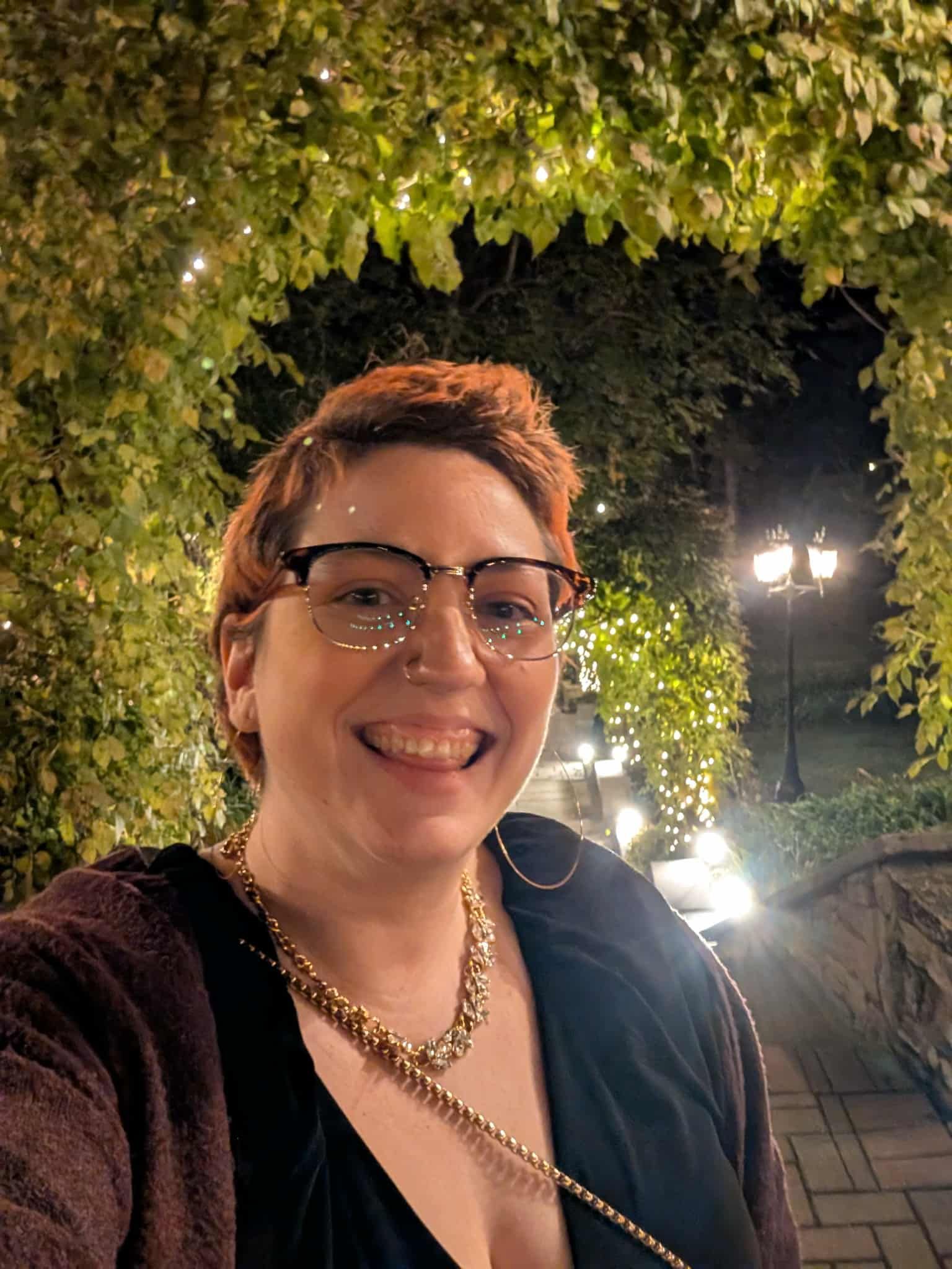 A white person with short orange hair and large black framed glasses smiling