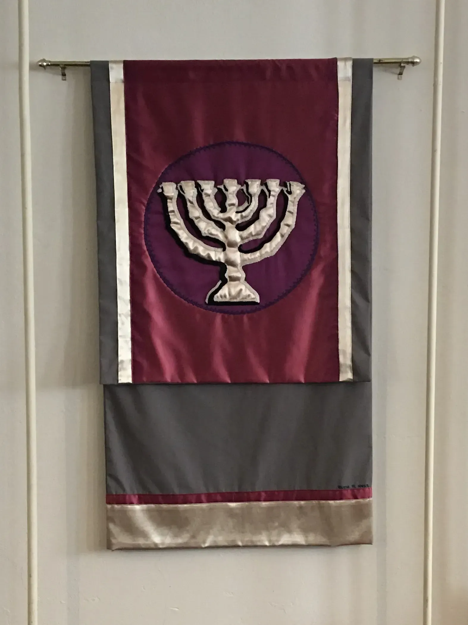 Maroon banner with a silver menorah in the middle