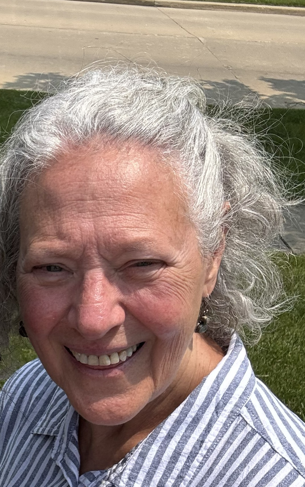 A white older woman with gray long hair smiling at the camera