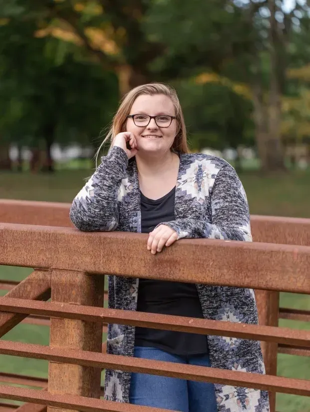 Autumn Haskins is a blonde young woman in a grey and white cardigan wearing glasses.
