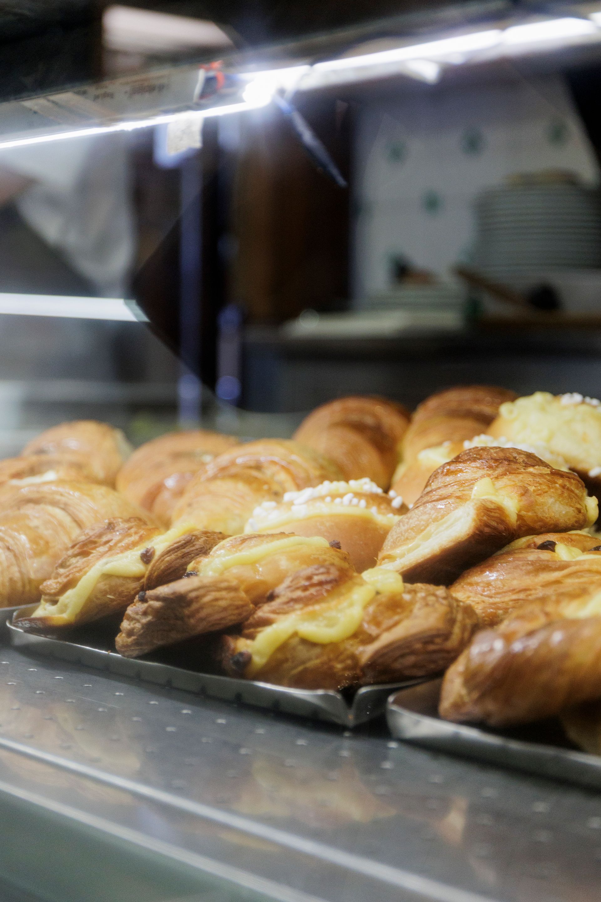 In una pasticceria, la vetrina è piena di file di pasticcini freschi, dorati e ripieni di crema.