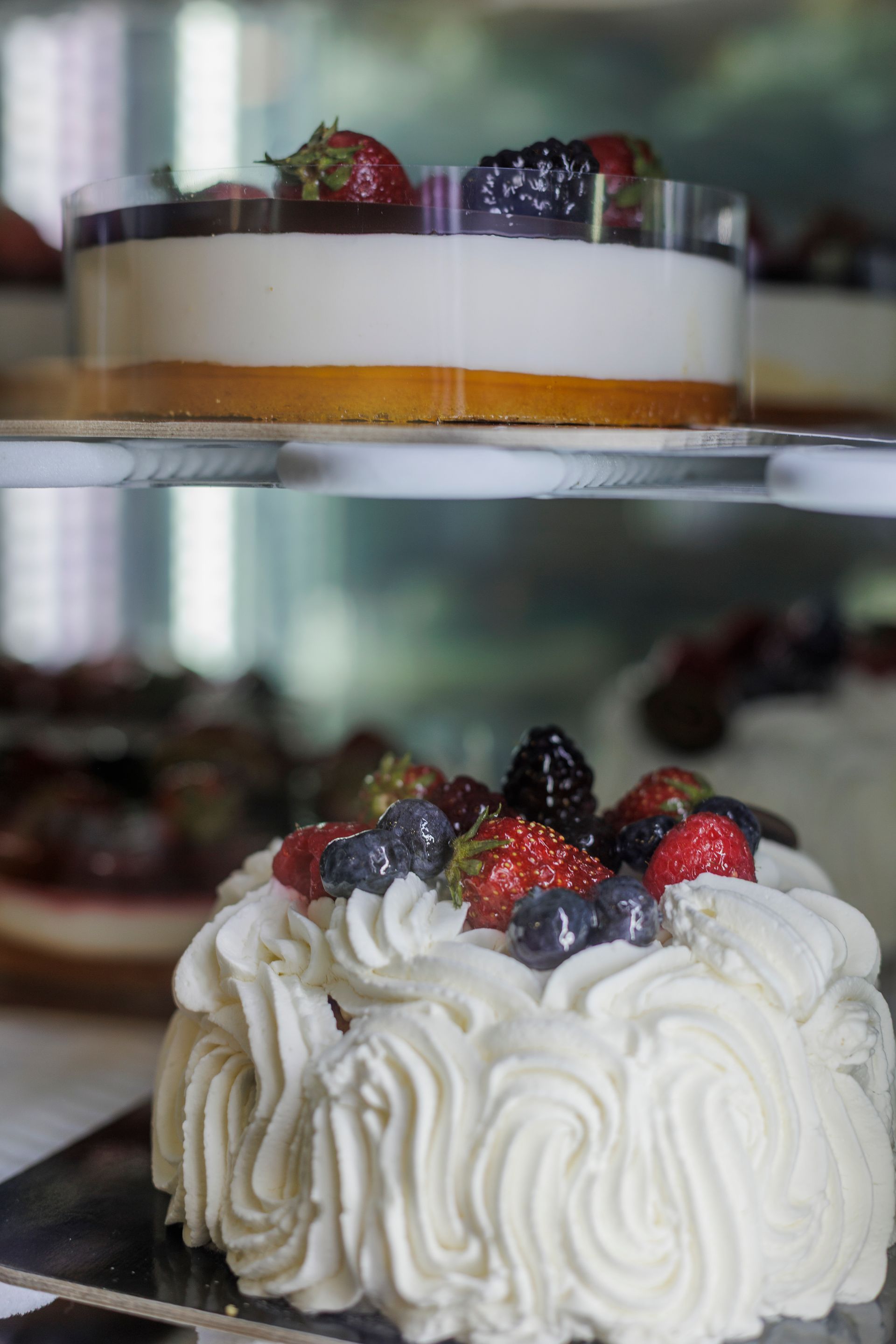 Sopra una torta in primo piano, decorata con glassa bianca e frutti di bosco assortiti, si trova una torta a strati con frutti di bosco.
