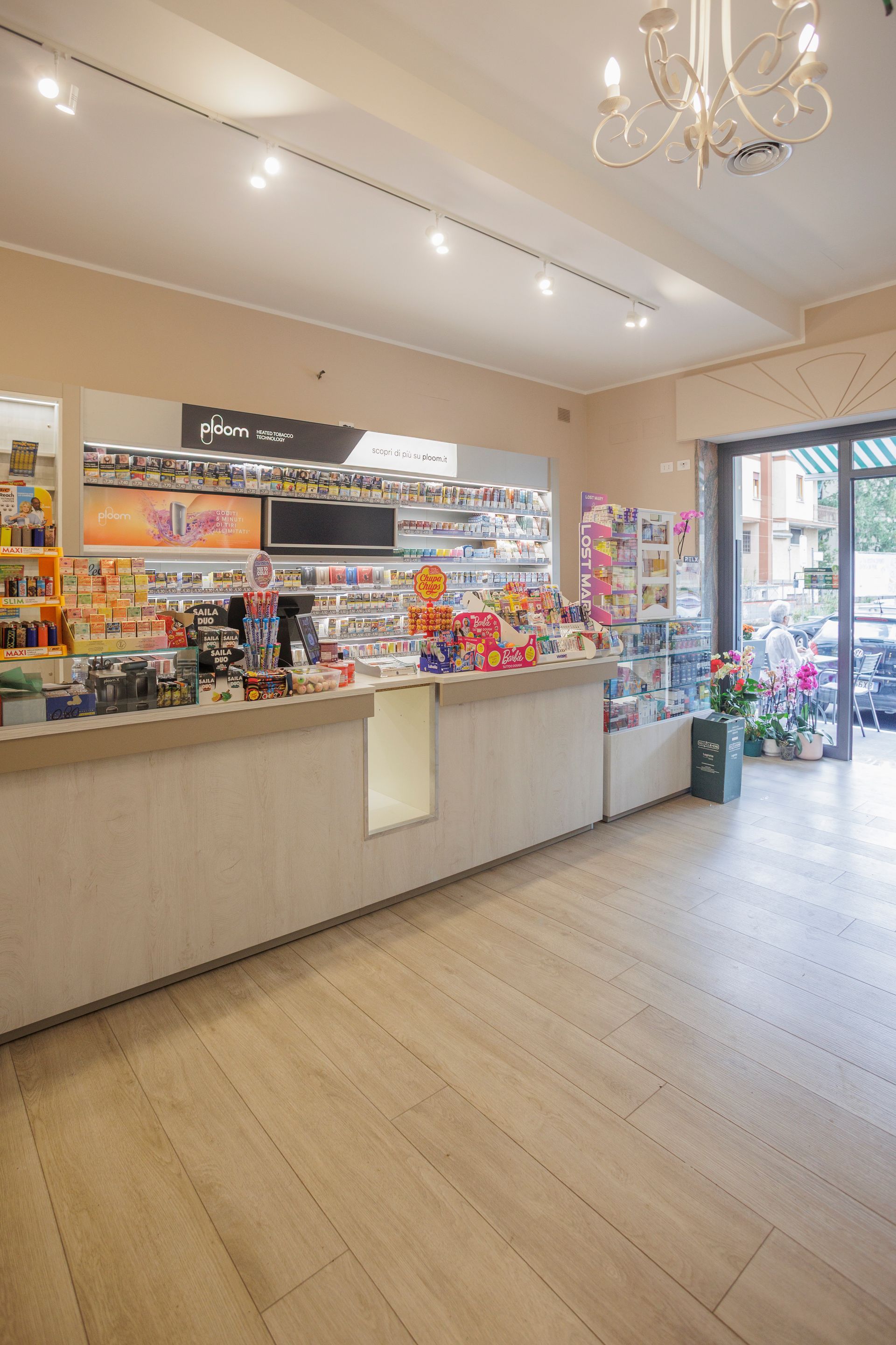L'interno di un negozio ben illuminato presenta un lungo bancone di servizio, vetrine per la merce e un ingresso con pannelli in vetro.