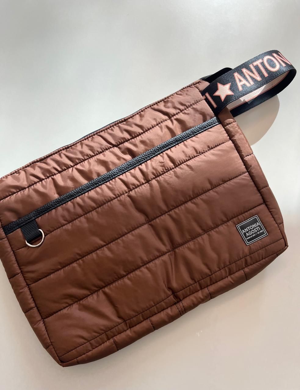 Una pila de cuatro bolsos acolchados con cierre de cremallera en verde oscuro, rosa brillante,