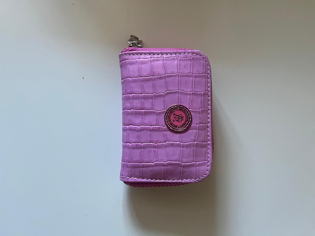 Una pequeña cartera rectangular de color rosa con textura en relieve de cocodrilo