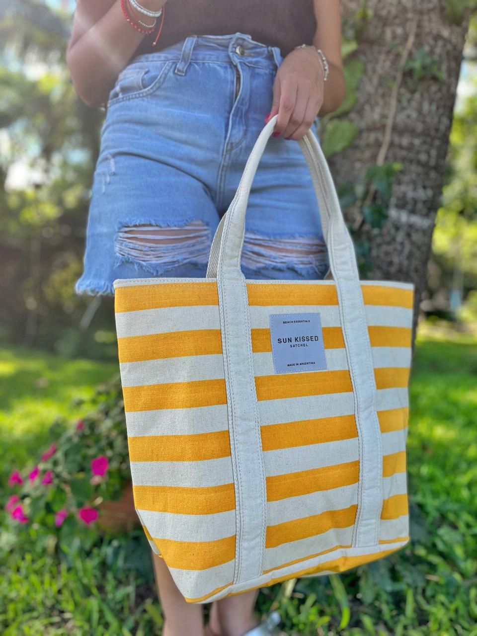 Una persona vestida de marrón sostiene una bolsa con cremallera a rayas amarillas