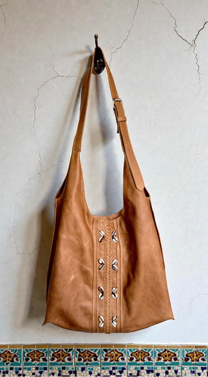Un bolso estilo hobo holgado de gamuza color tostado con detalles de tachuelas plateadas