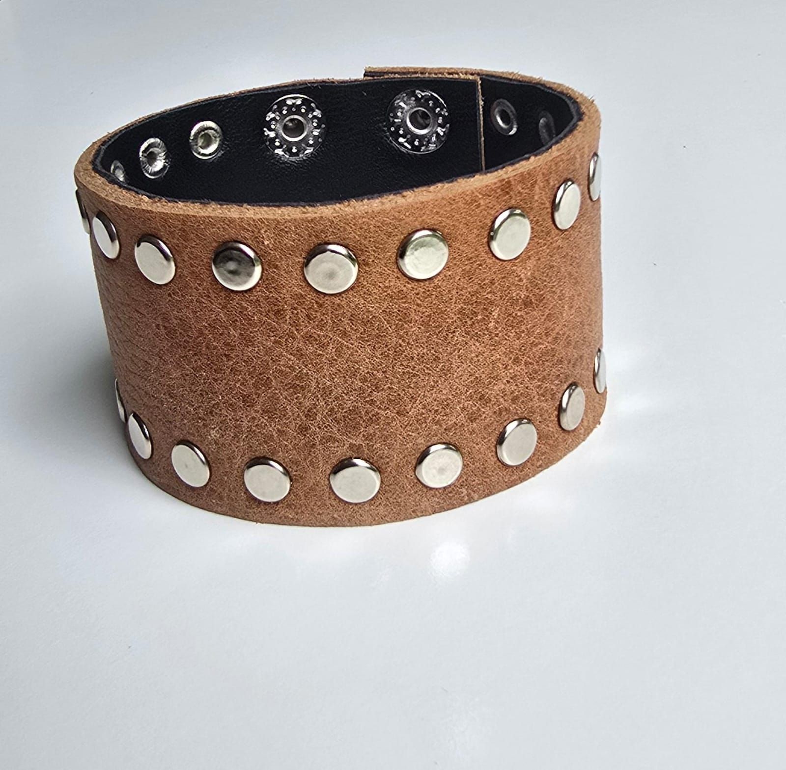 Una pulsera ancha de cuero texturizado de color marrón que presenta dos filas