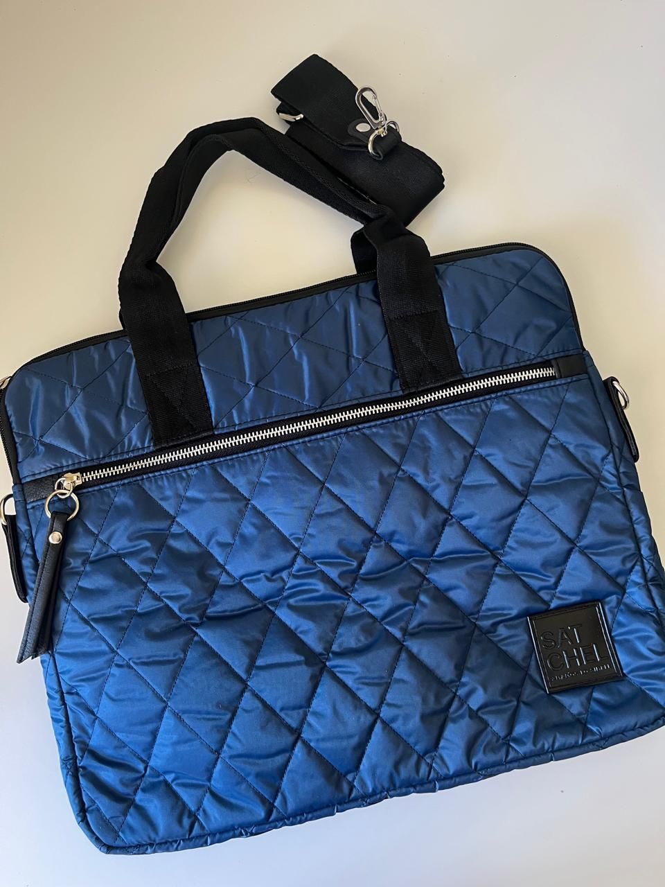 Un bolso para portátil acolchado de color azul marino con asas negras, un compartimento con cremallera