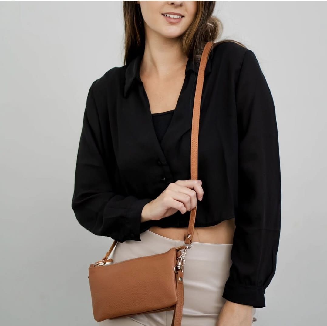 Una persona viste una camisa negra abotonada y pantalones de color claro