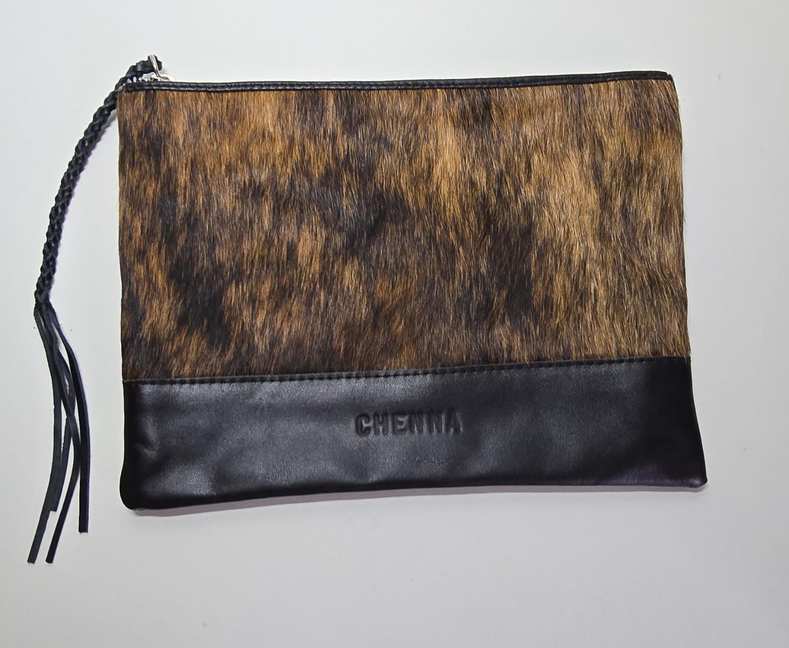 Un bolso de mano rectangular con una parte superior de pelo atigrado marrón y una parte inferior de cuero negro, que presenta