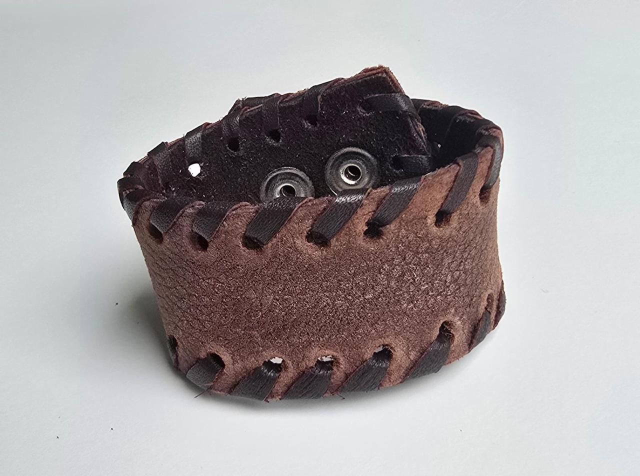 Una pulsera de cuero marrón que presenta un patrón de cordones a lo largo de sus bordes