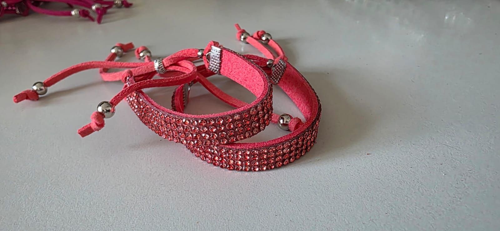Dos pulseras de ante color coral adornadas con filas de cristales brillantes