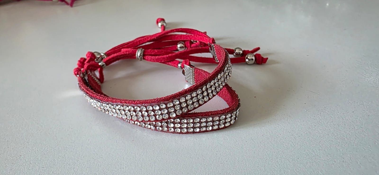 Una pulsera envolvente hecha de gamuza roja con tres filas de diamantes de imitación incrustados,
