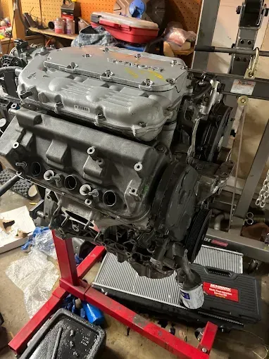 A clean, organized car engine compartment featuring a black engine cover, a battery, and various fluid reservoirs.