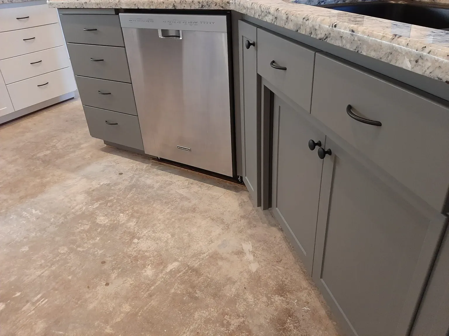 A kitchen with gray cabinets and a stainless steel dishwasher