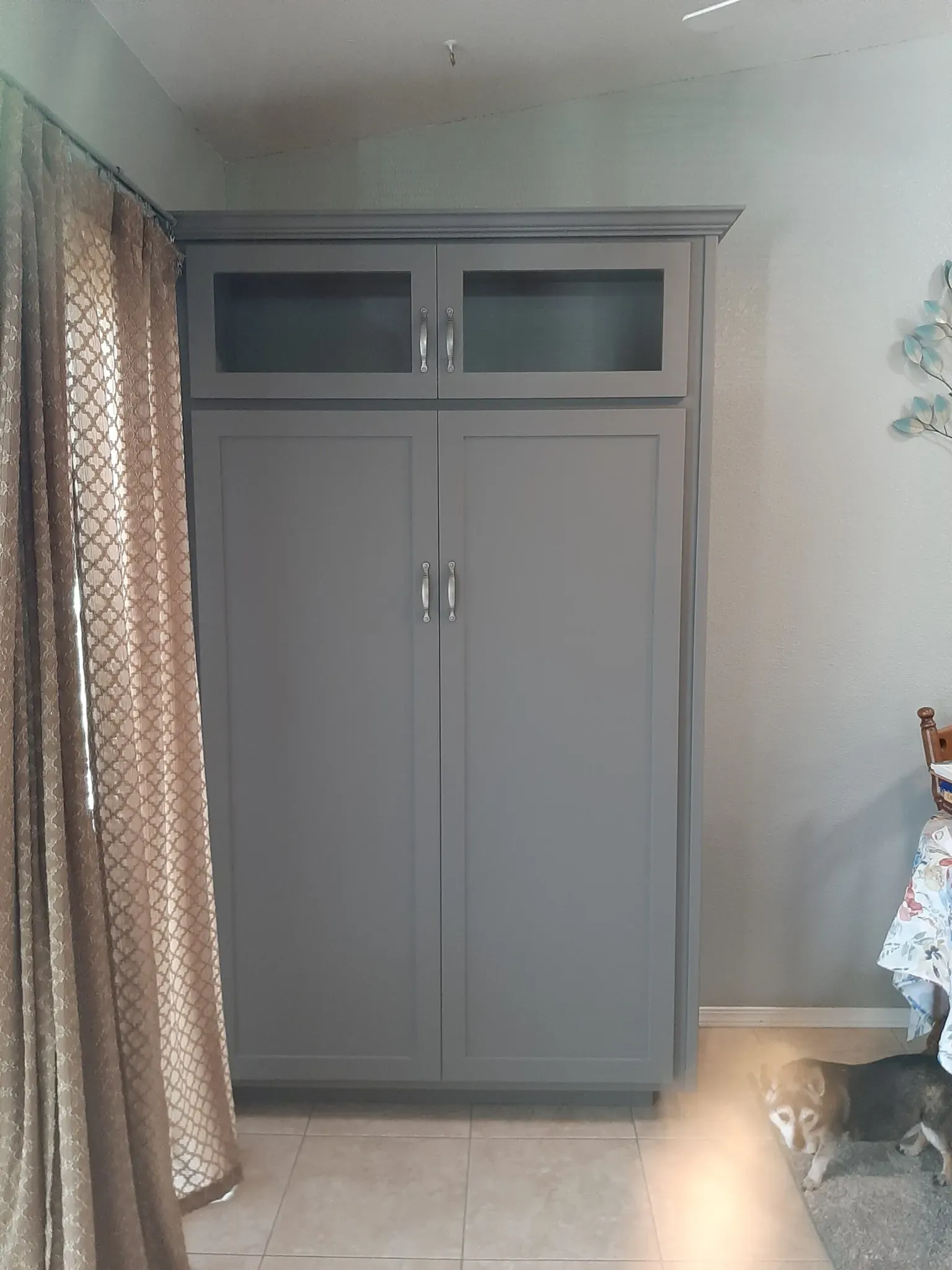 A gray cabinet is sitting in a room next to a window.