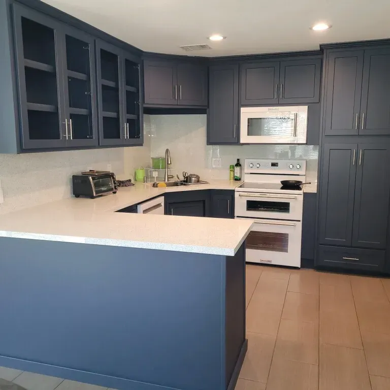 A kitchen with blue cabinets and white counter tops
