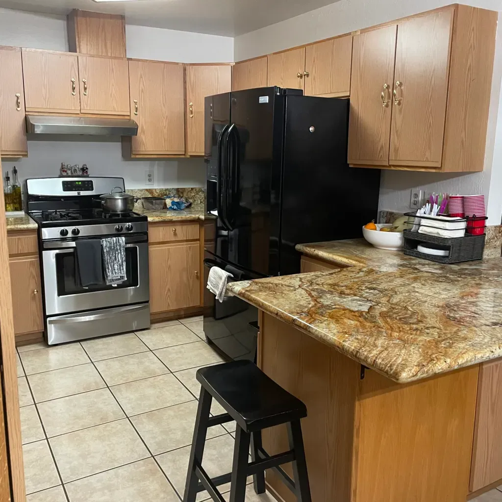 A kitchen with wooden cabinets and a black refrigerator