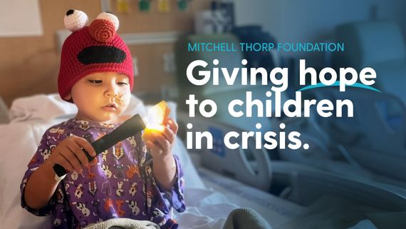 A child in a red Elmo hat holds a flashlight in a hospital bed next to the text 