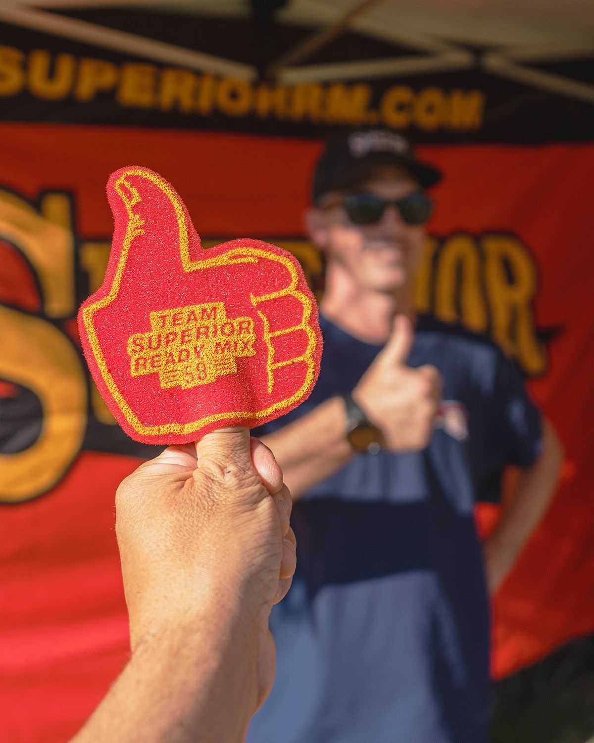 A person is holding up a red foam thumbs up sign