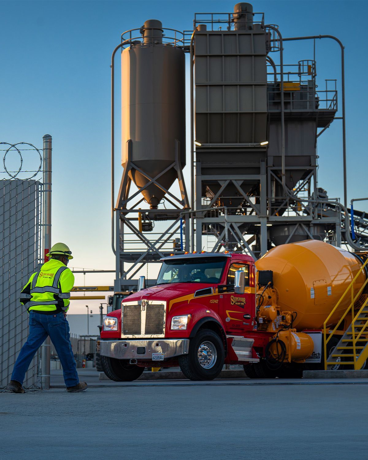A red truck is parked in front of a cement plant
