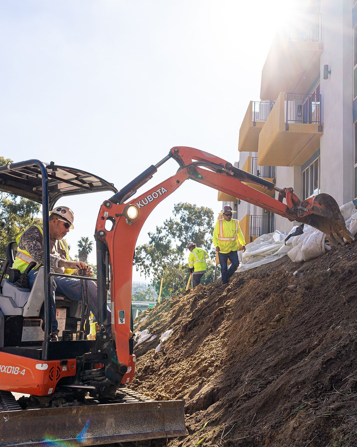 A man is driving a small excavator on a dirt hill.