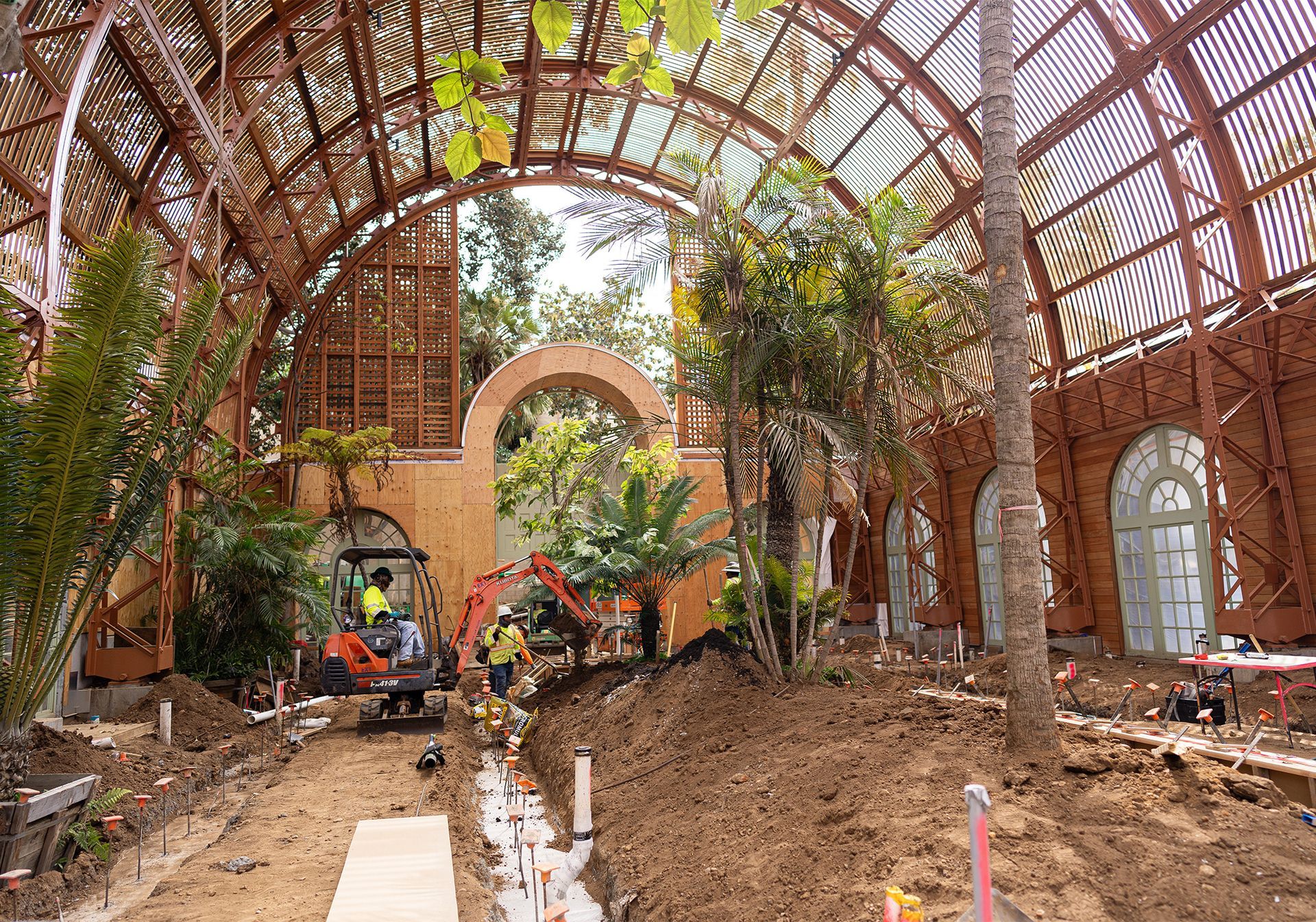 A large building is being built with a lot of plants and trees.