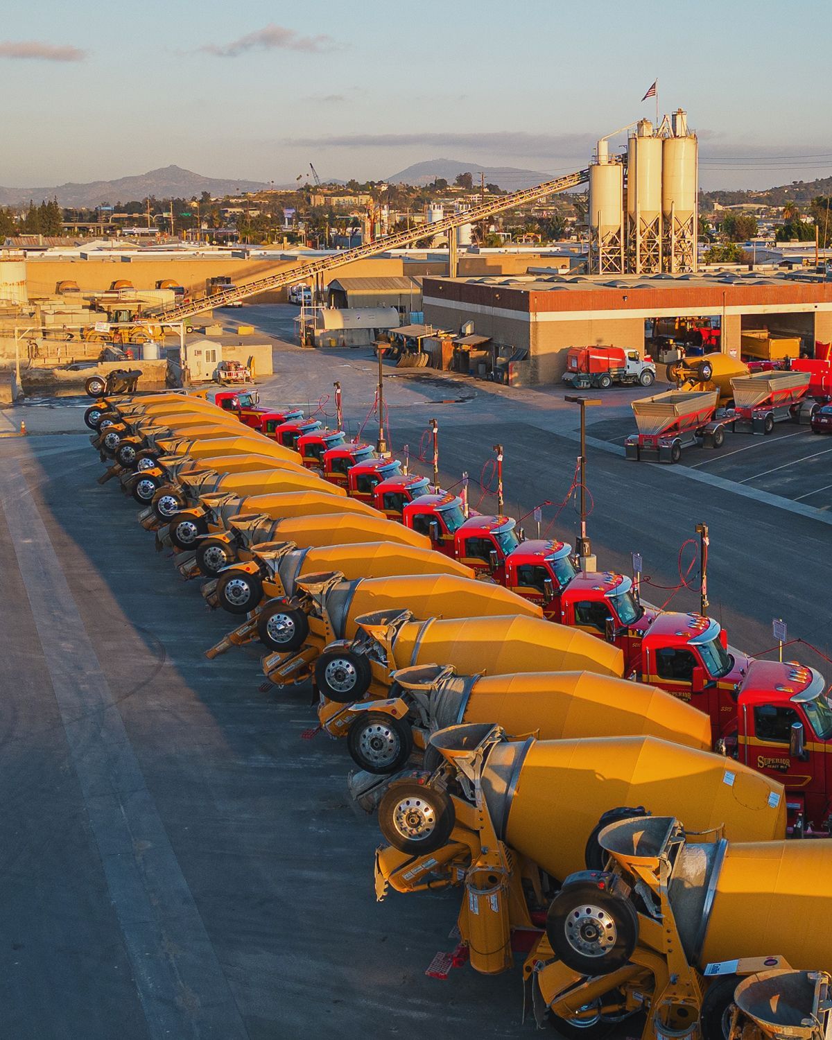 A row of yellow and red trucks are parked in a parking lot