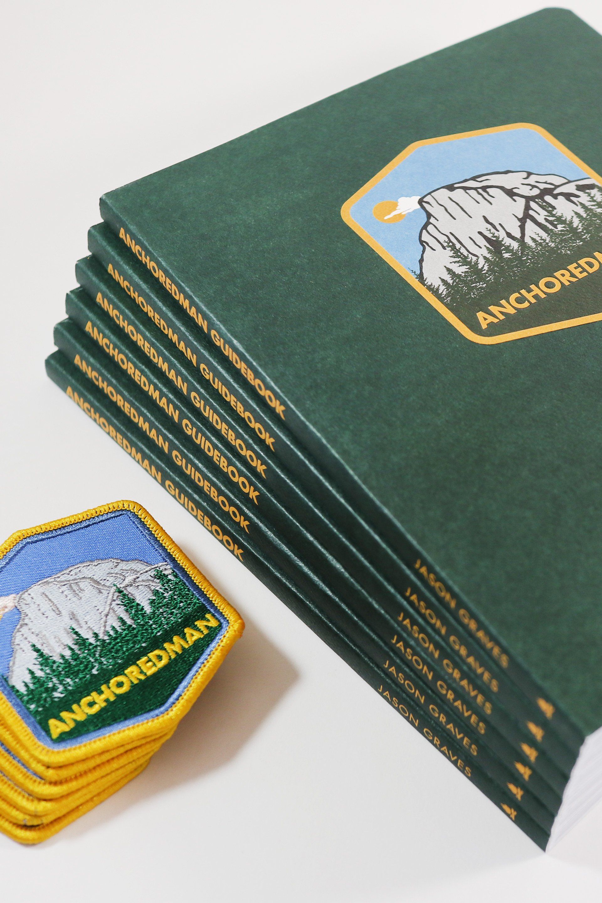A stack of anchoredman books next to a patch