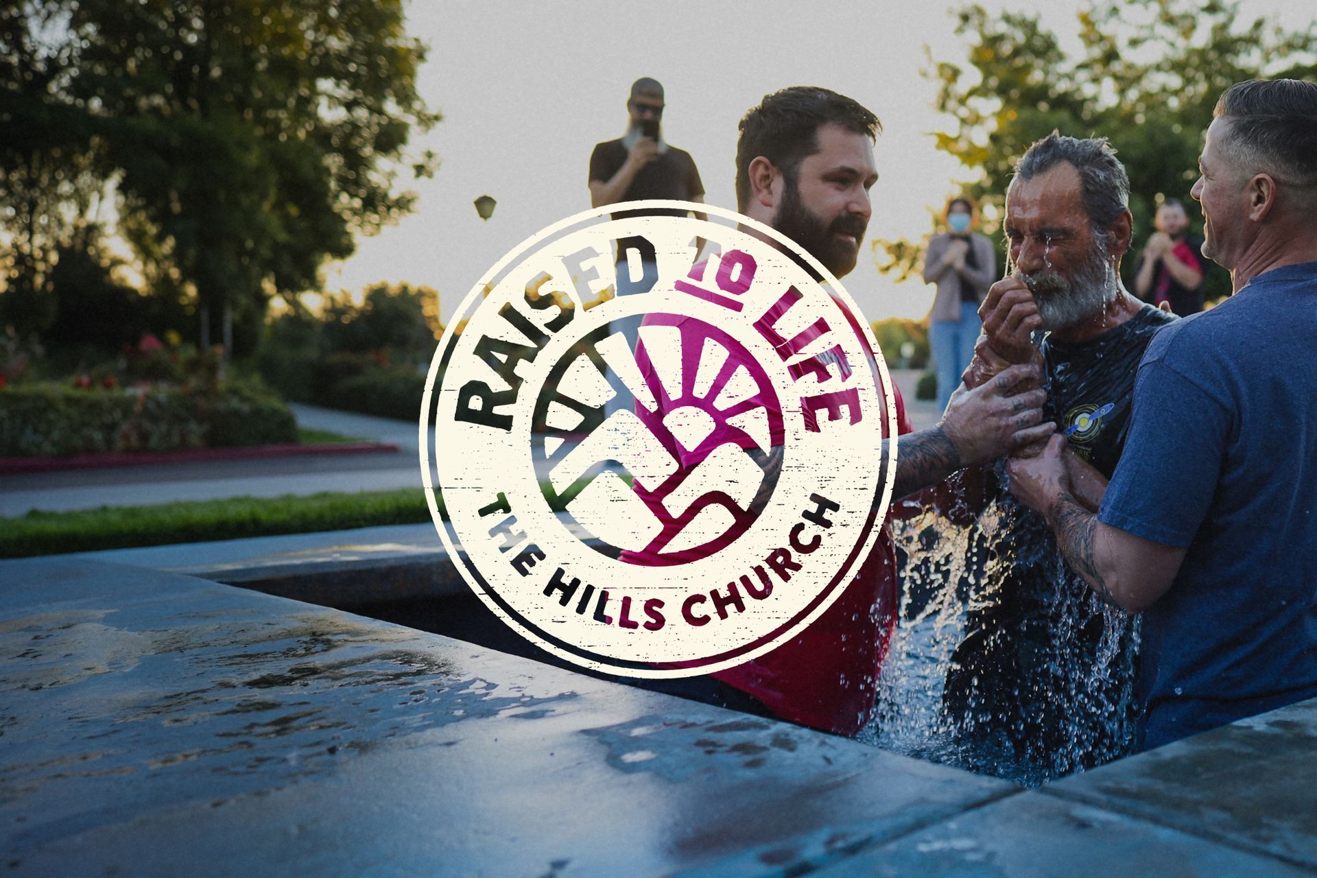 A man is being baptized by a group of people at the hills church.