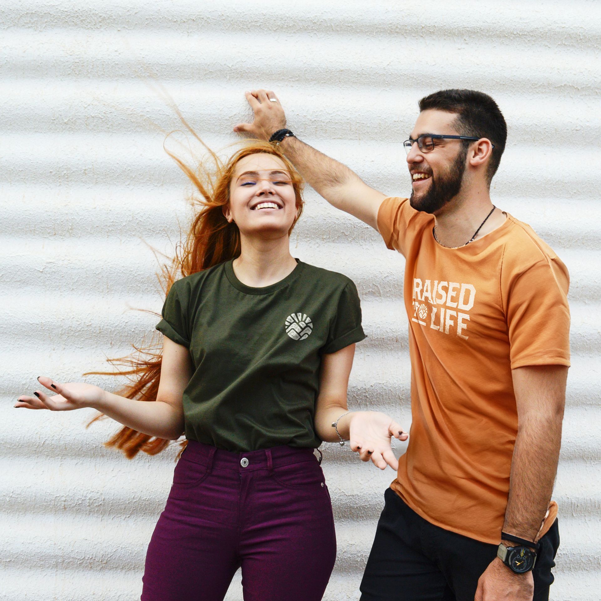 A man and a woman are standing next to each other and the man is wearing a shirt that says raised to life