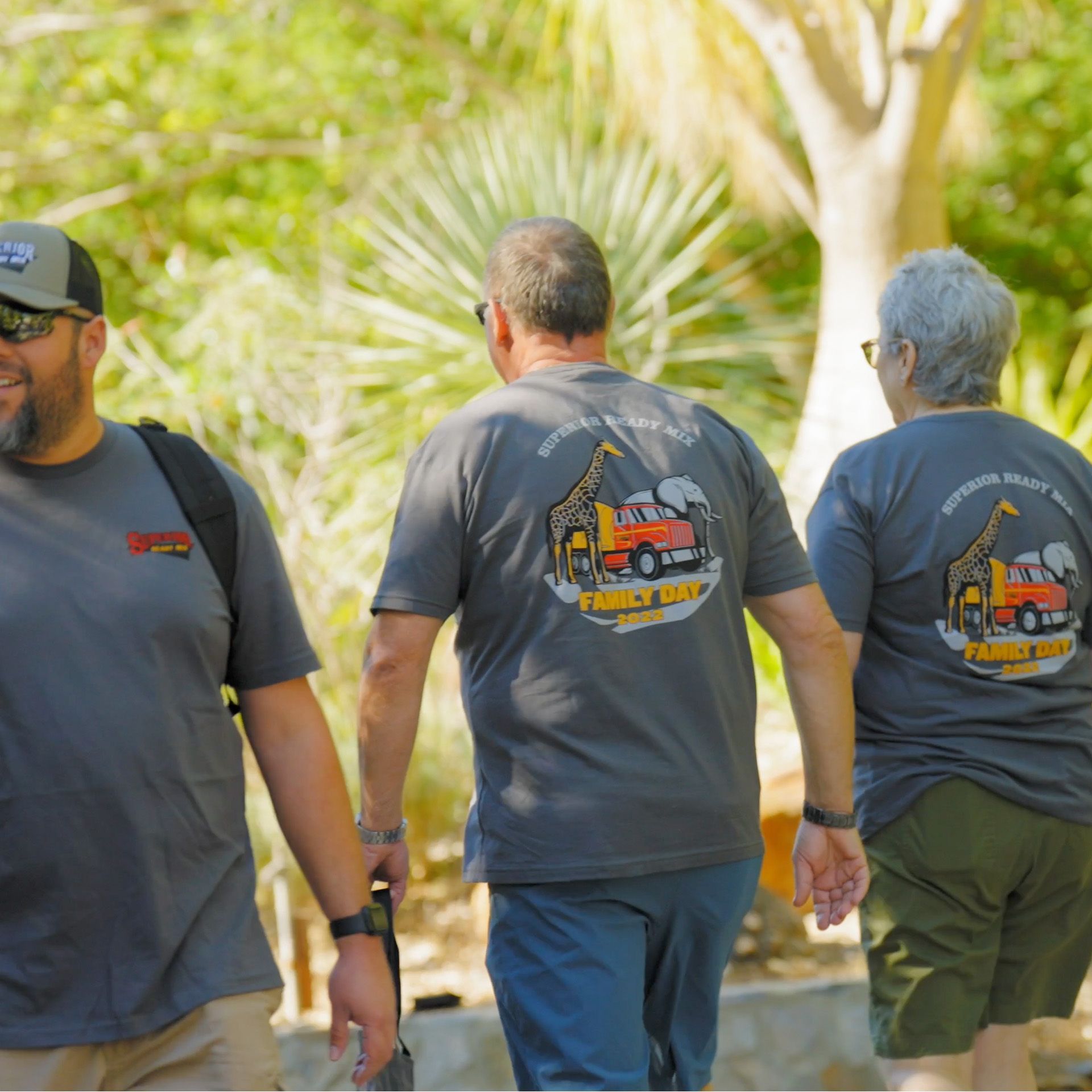 A group of people are walking and one of their shirts has a truck on it