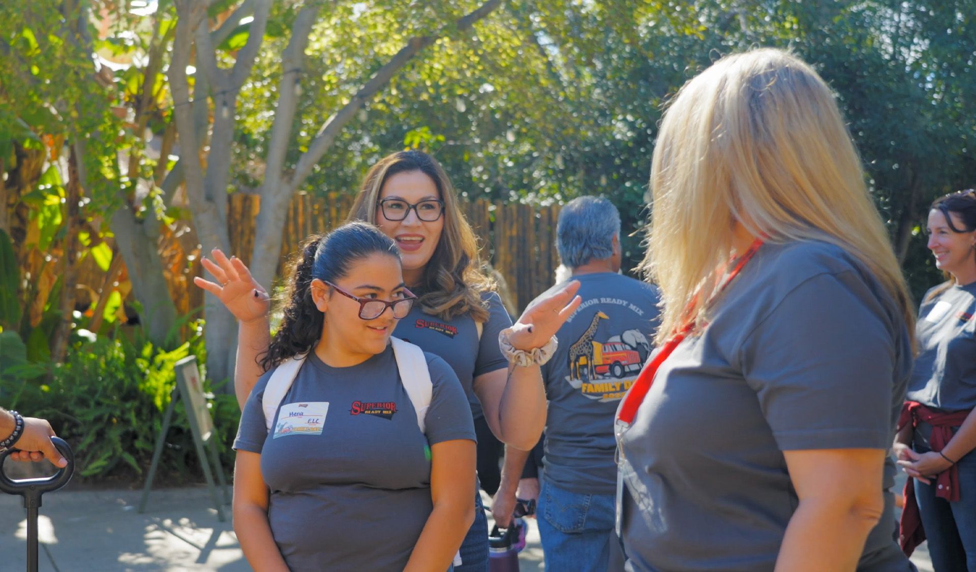 A group of women are standing in a park talking to each other.
