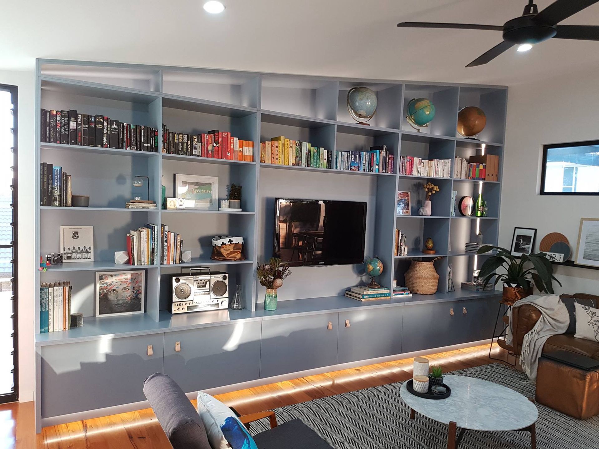 A living room with a lot of shelves and a ceiling fan. — Concept Kitchens In Bonny Hills, NSW