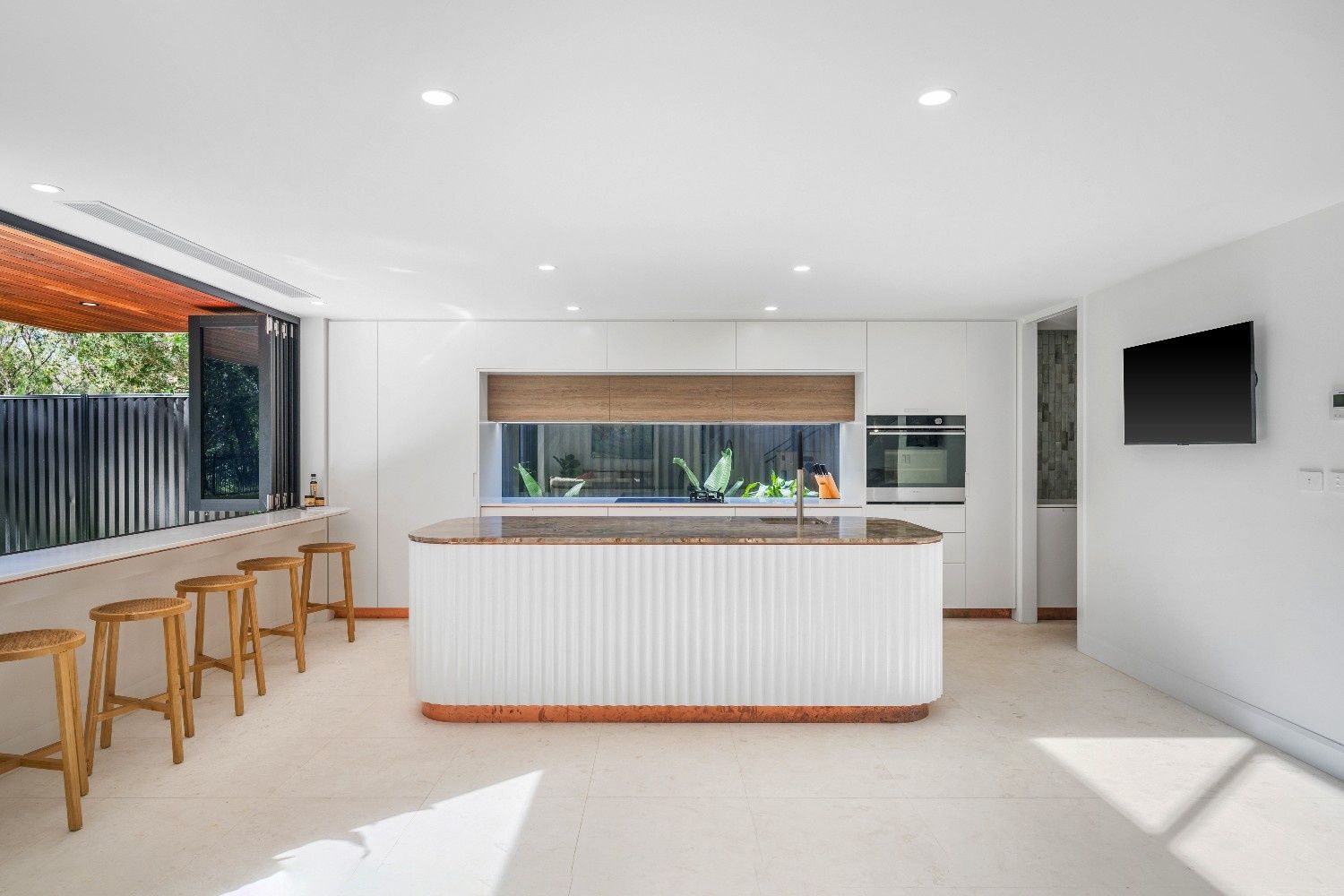 Modern White Kitchen with Curved Island, Bar Seating, and Open Window to Outdoor Space — Concept Kitchens In Port Macquarie, NSW