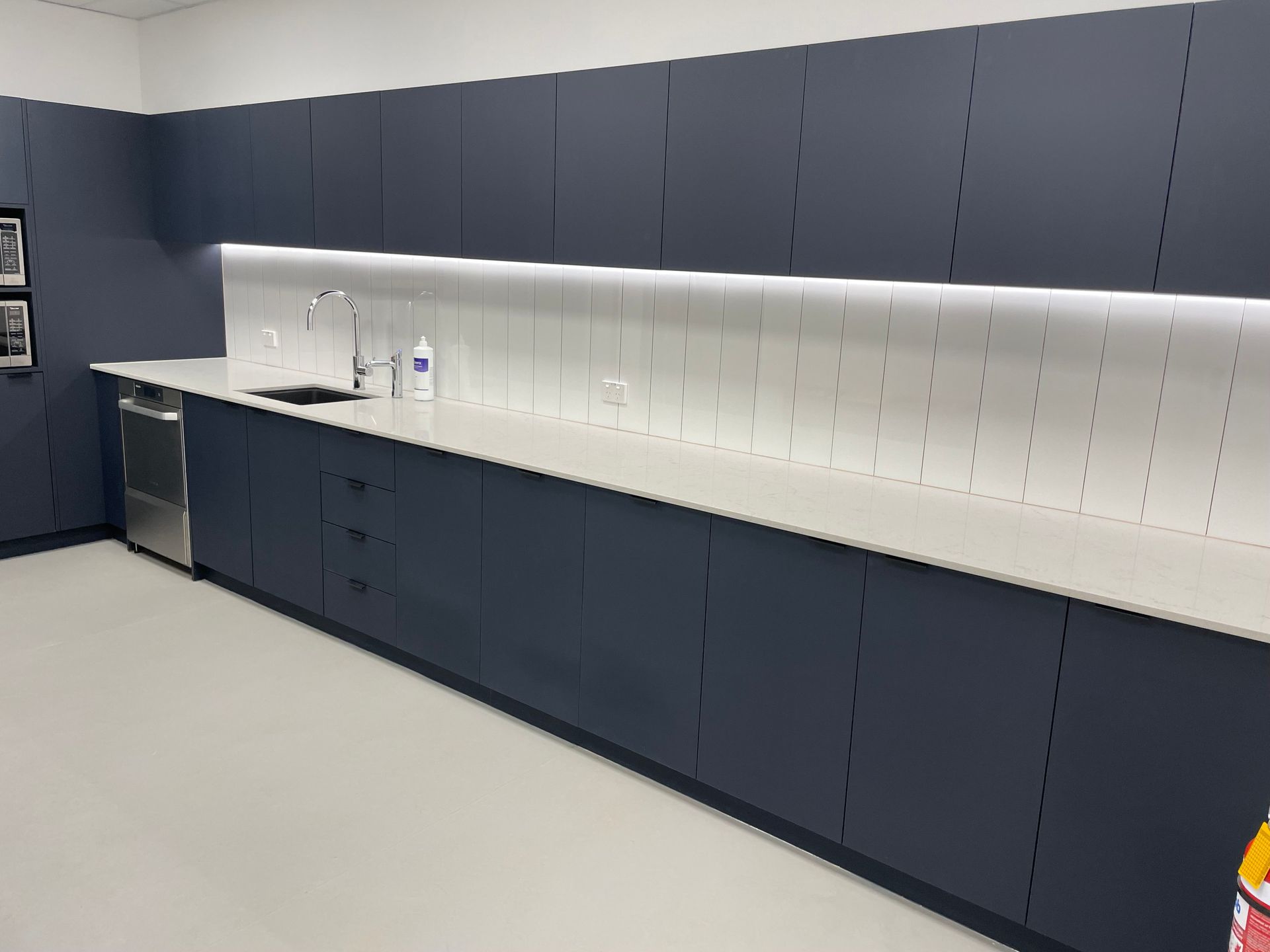 A Long Kitchen With Gray Cabinets And White Counter Tops — Concept Kitchens In Port Macquarie, NSW