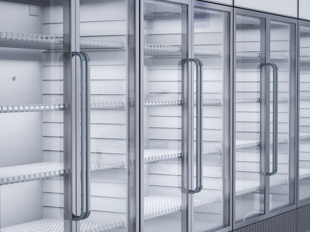 Empty glass-door refrigerator cases in a store aisle