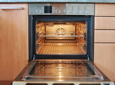 Open oven with interior light on in a modern kitchen